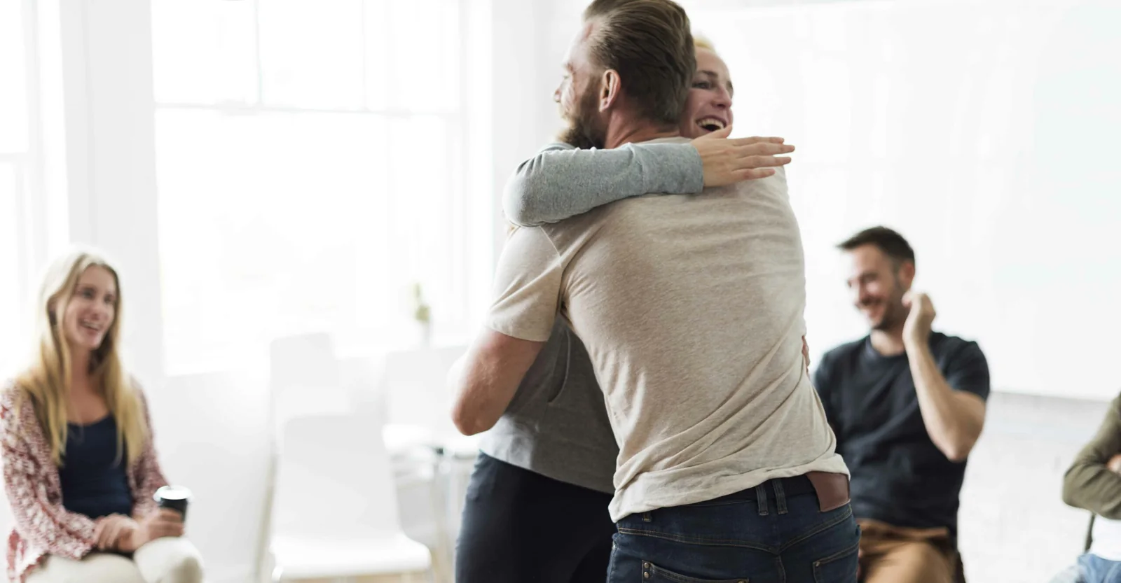 Two people embracing in a treatment group session