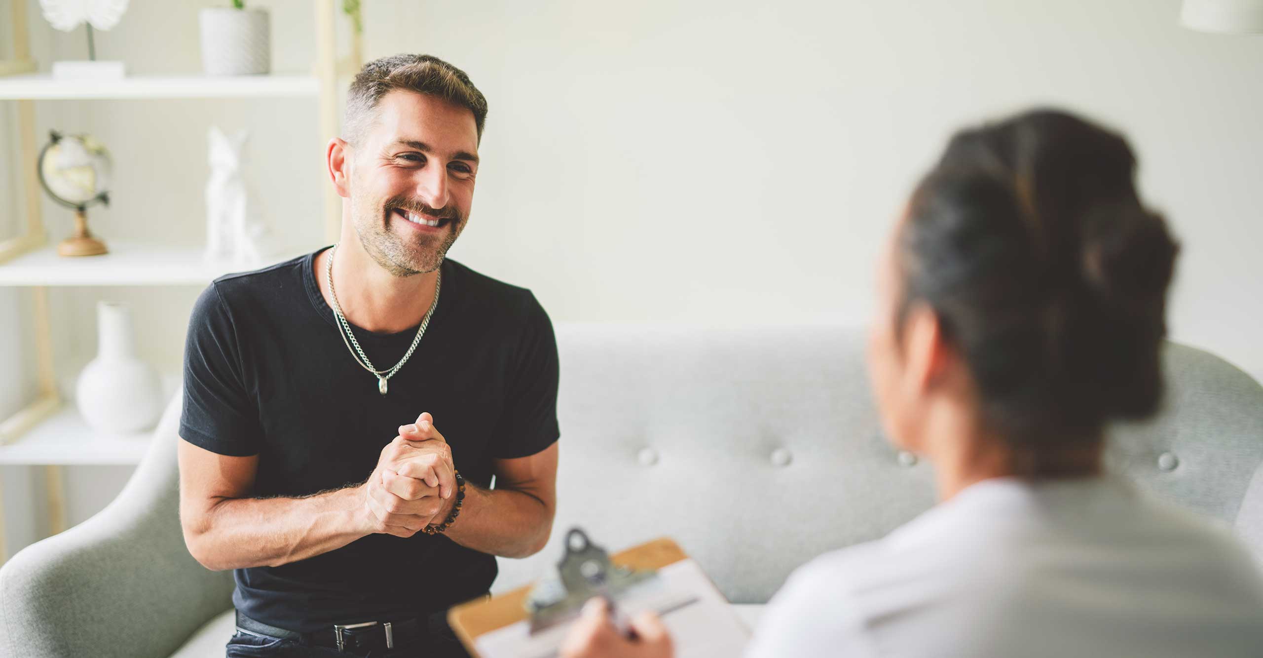 A man in therapy with a psychologist smiling having overcome a co-occurring condition.